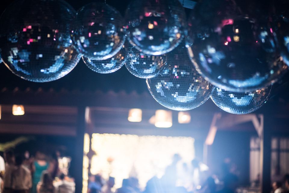 Pista de dança de festa com vários globos espelhados pendurados sobre os convidados