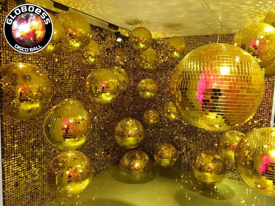 Sala decorada com dezenas de globos espelhados dourados de vários tamanhos